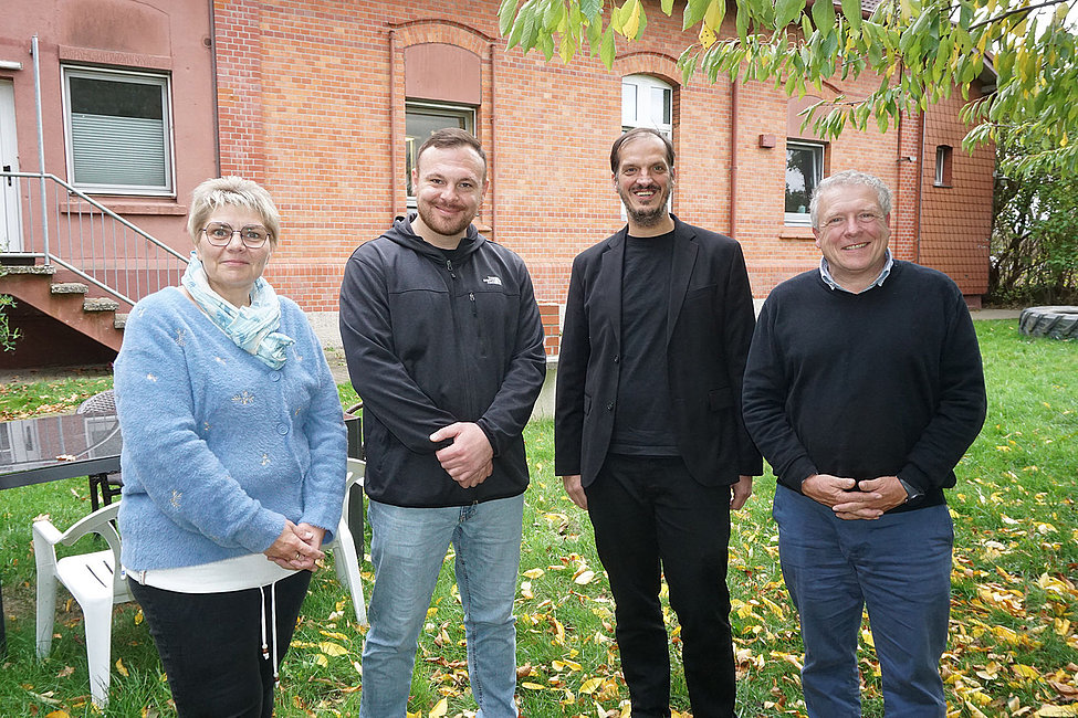 Vier Teilnehmende einer Diskussion stehen vor Backsteinhaus